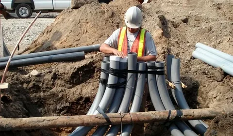 Professional underground utility installation crew installing pipes and conduits safely