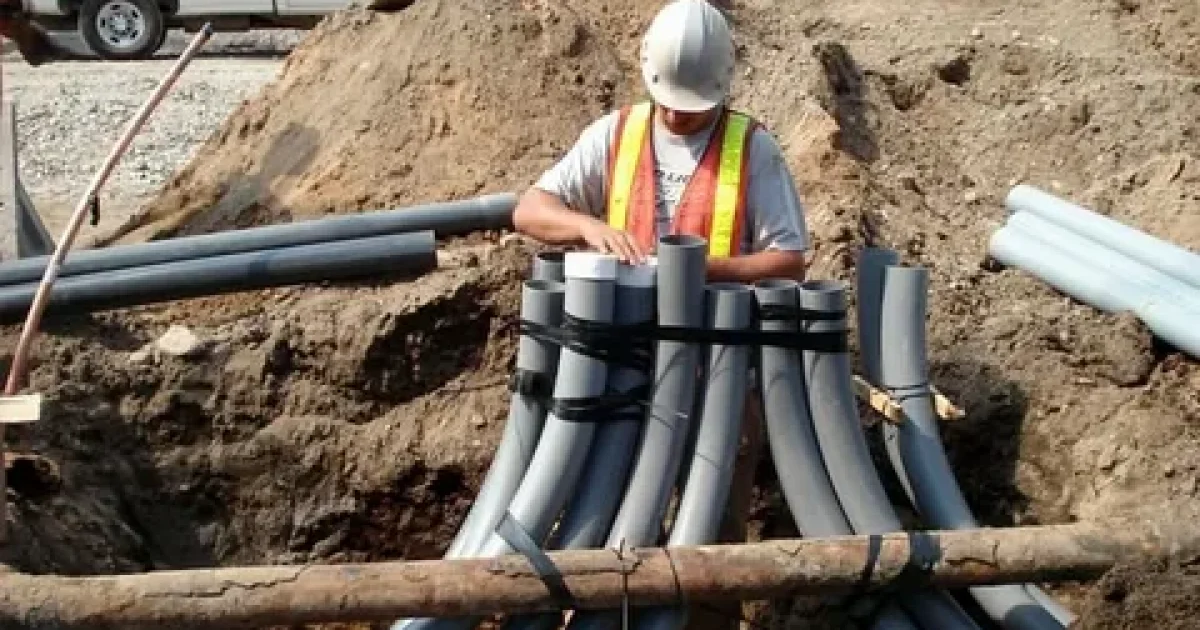 Professional underground utility installation crew installing pipes and conduits safely